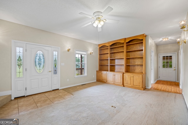 entryway with a textured ceiling, ceiling fan, and light colored carpet