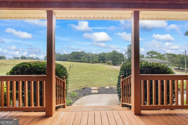 wooden terrace with a rural view and a lawn