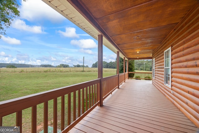 wooden terrace with a rural view and a yard