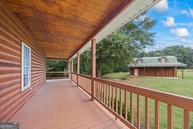 wooden terrace featuring a lawn and a porch