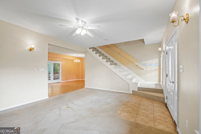 unfurnished living room with light carpet, a textured ceiling, ceiling fan with notable chandelier, and french doors