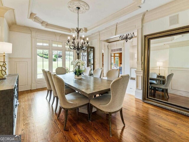 dining area featuring wood-type flooring, ornamental molding, a chandelier, and a wealth of natural light