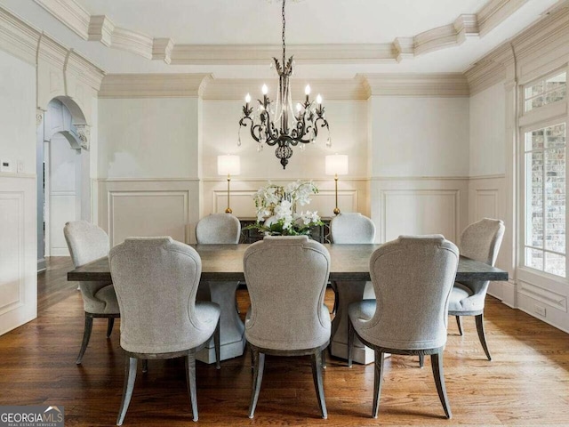 dining room with hardwood / wood-style flooring, crown molding, and a notable chandelier