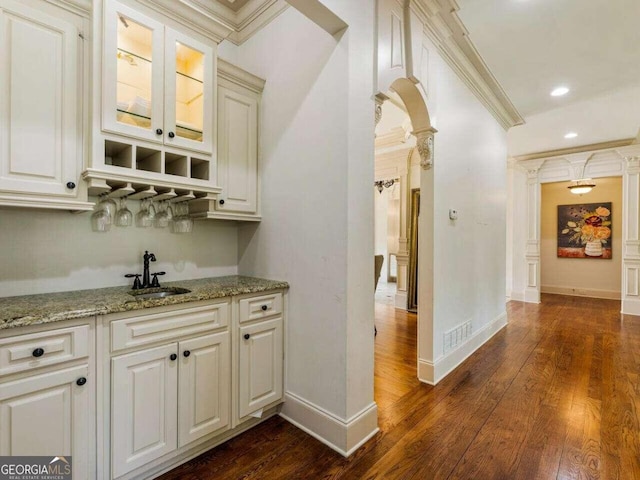 bar featuring light stone countertops, ornamental molding, dark hardwood / wood-style flooring, and sink