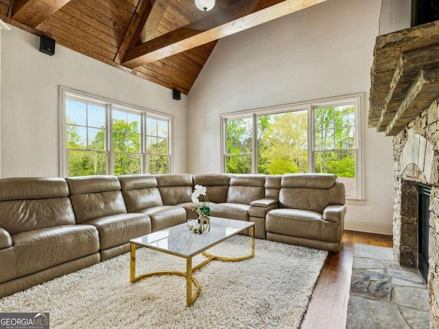 living room featuring wooden ceiling, beam ceiling, a stone fireplace, high vaulted ceiling, and hardwood / wood-style flooring