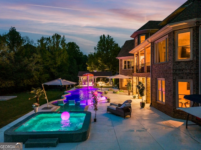 pool at dusk with an outdoor living space and a patio area