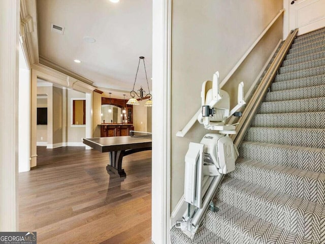 stairs featuring ornamental molding and hardwood / wood-style flooring