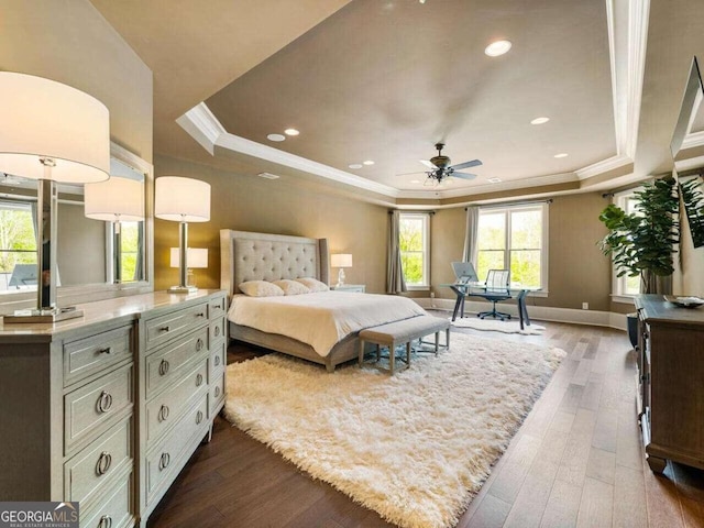 bedroom featuring dark wood-type flooring, crown molding, a tray ceiling, and ceiling fan