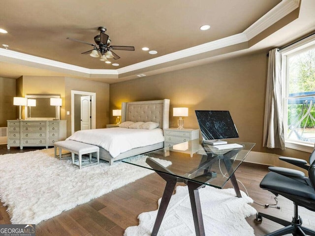 bedroom with ceiling fan, a tray ceiling, hardwood / wood-style floors, and ornamental molding