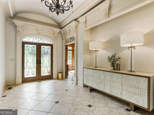 tiled foyer featuring french doors, lofted ceiling, crown molding, and a chandelier