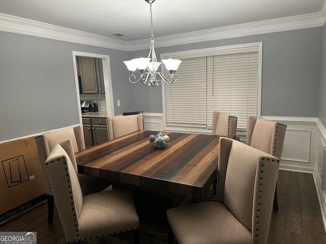 dining area with an inviting chandelier, ornamental molding, and dark hardwood / wood-style flooring