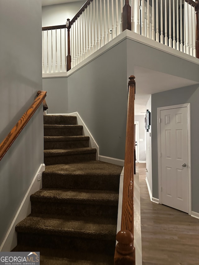 staircase with a high ceiling and hardwood / wood-style floors