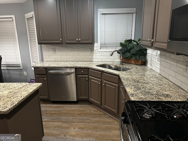 kitchen featuring sink, appliances with stainless steel finishes, dark brown cabinetry, dark hardwood / wood-style flooring, and light stone countertops