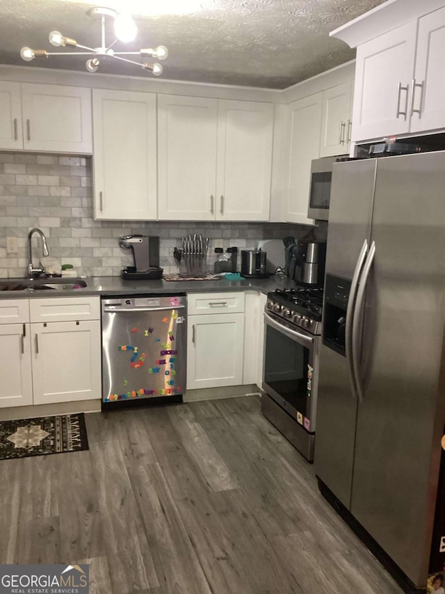 kitchen with dark wood-type flooring, sink, white cabinetry, backsplash, and appliances with stainless steel finishes