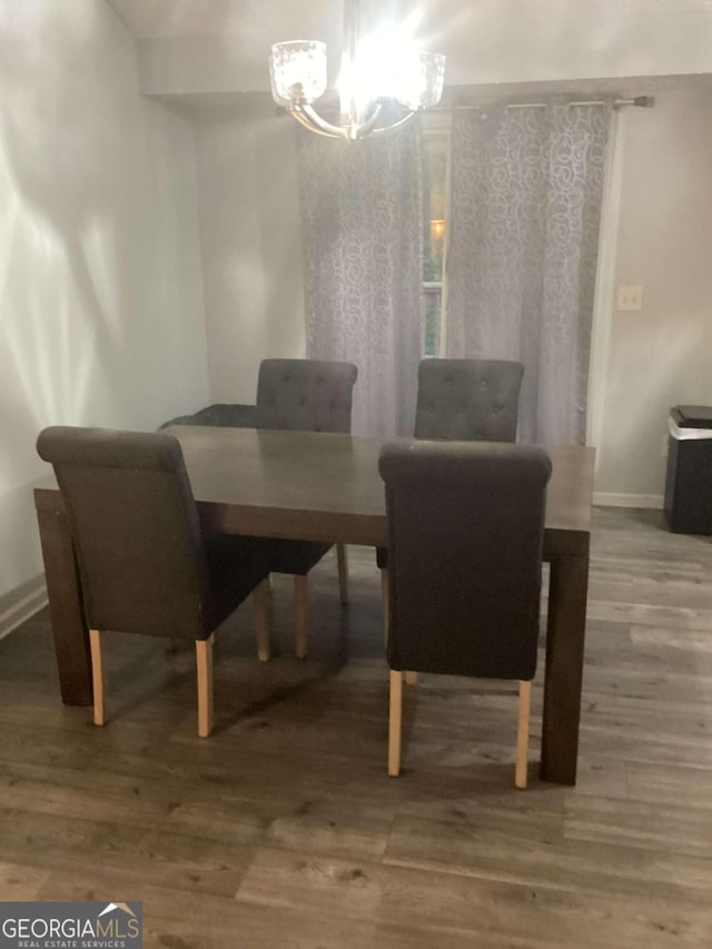 dining area with wood-type flooring and a notable chandelier