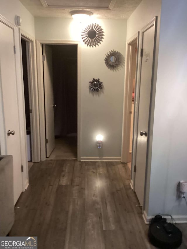 hallway with a textured ceiling and dark hardwood / wood-style flooring