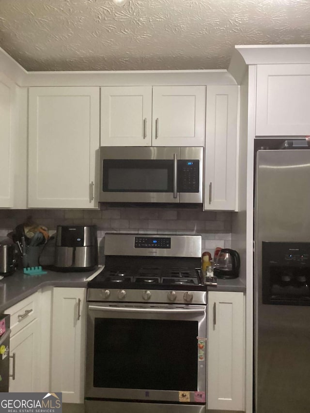 kitchen featuring a textured ceiling, backsplash, white cabinetry, and stainless steel appliances