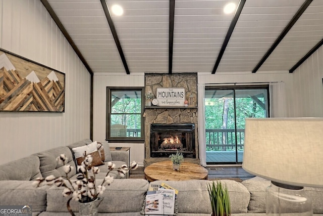 living room with a fireplace, plenty of natural light, vaulted ceiling with beams, and wood-type flooring