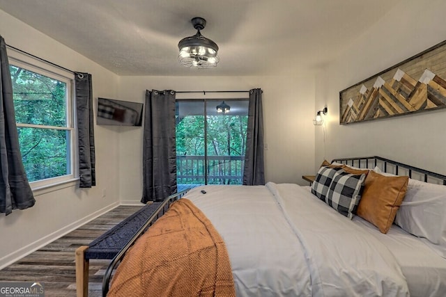 bedroom with access to exterior and dark hardwood / wood-style flooring