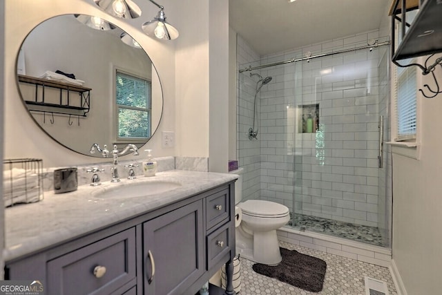 bathroom with tile patterned floors, a shower with shower door, vanity, and toilet