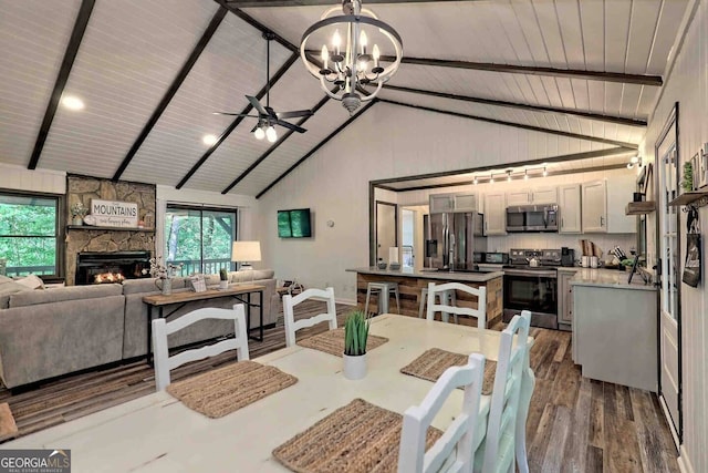 dining area featuring high vaulted ceiling, beam ceiling, a stone fireplace, and dark hardwood / wood-style floors