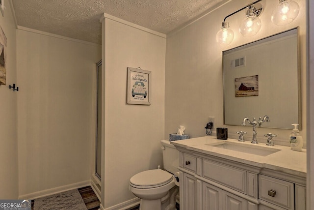 bathroom with vanity, toilet, a shower with shower door, and a textured ceiling