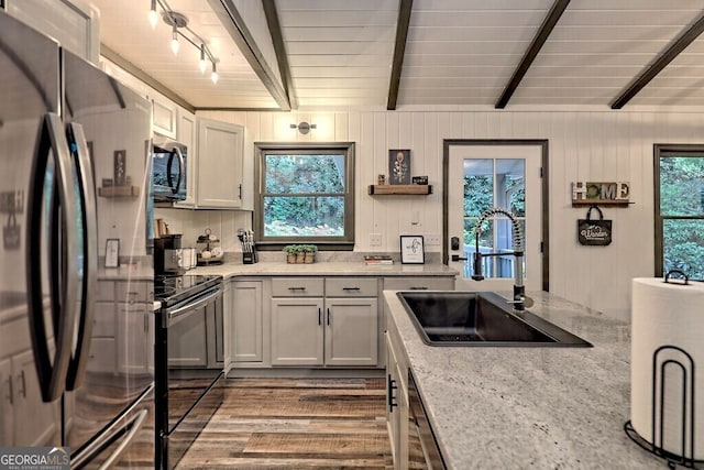 kitchen featuring white cabinets, beam ceiling, sink, appliances with stainless steel finishes, and light wood-type flooring