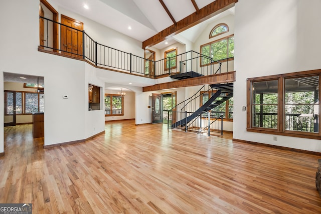 living room featuring beam ceiling, a notable chandelier, hardwood / wood-style flooring, and high vaulted ceiling