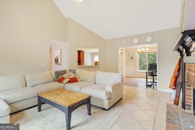 living room with a fireplace, light tile patterned floors, an inviting chandelier, and high vaulted ceiling