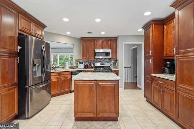 kitchen with light stone counters, a center island, light tile patterned floors, and appliances with stainless steel finishes