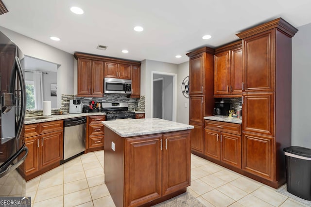 kitchen with a center island, light tile patterned flooring, light stone countertops, and appliances with stainless steel finishes