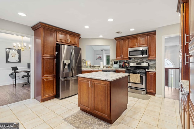 kitchen featuring light tile patterned flooring, appliances with stainless steel finishes, tasteful backsplash, a notable chandelier, and a kitchen island