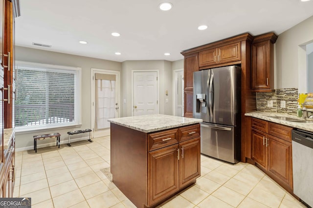 kitchen featuring a center island, decorative backsplash, light tile patterned floors, light stone counters, and stainless steel appliances