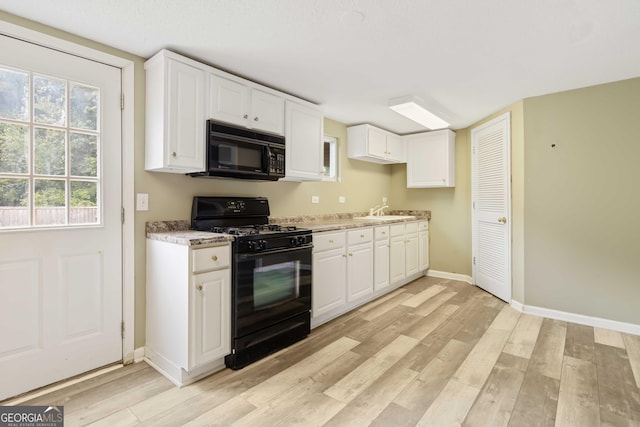 kitchen with light hardwood / wood-style floors, white cabinetry, and black appliances