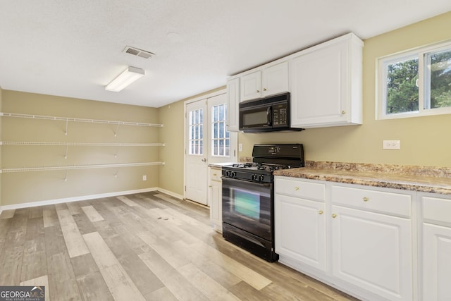 kitchen with black appliances, light wood-type flooring, white cabinetry, and french doors