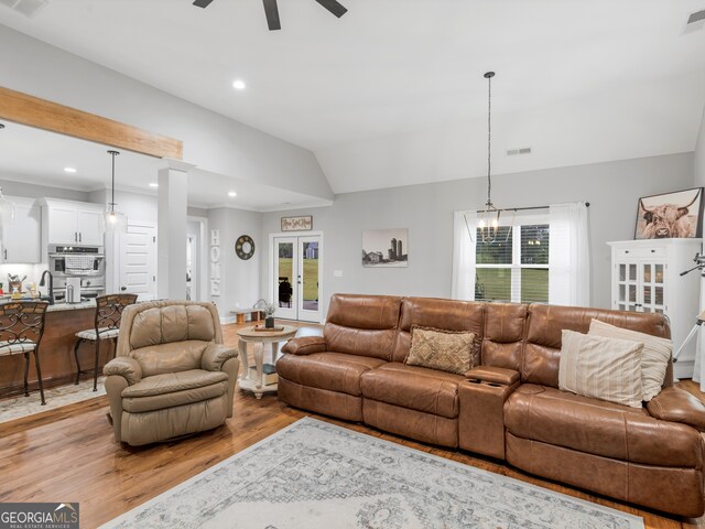 living room with light wood-type flooring, vaulted ceiling, ceiling fan, and plenty of natural light