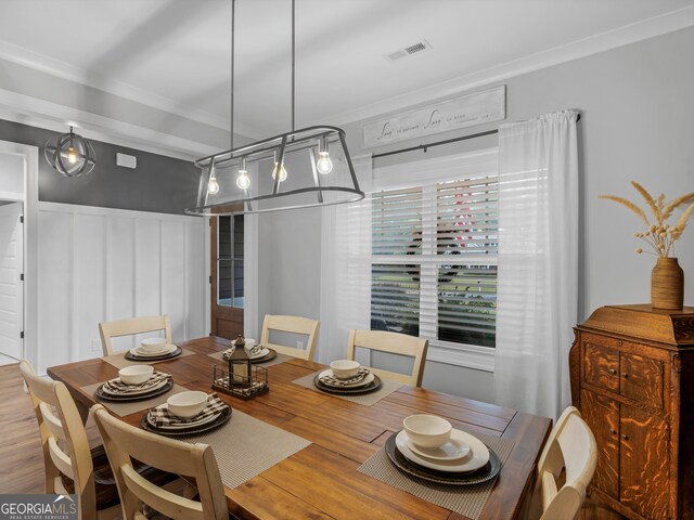 dining area with wood-type flooring and ornamental molding