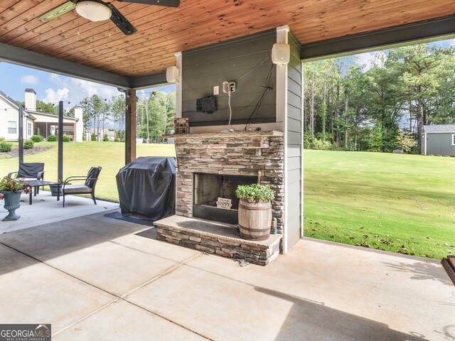 view of patio featuring ceiling fan, an outdoor stone fireplace, and a grill