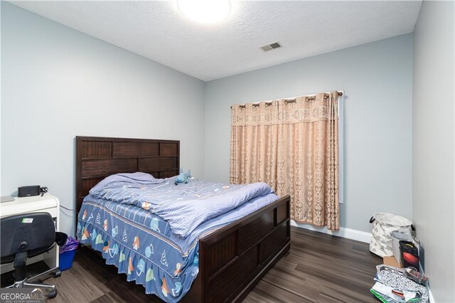 bedroom with a textured ceiling and dark wood-type flooring