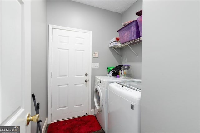 washroom with a textured ceiling and washing machine and clothes dryer