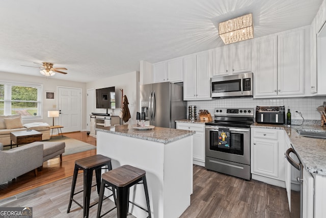 kitchen featuring stainless steel appliances, white cabinetry, a kitchen island, and dark hardwood / wood-style flooring