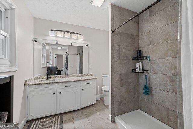 bathroom with vanity, a textured ceiling, a shower with shower curtain, tile patterned flooring, and toilet