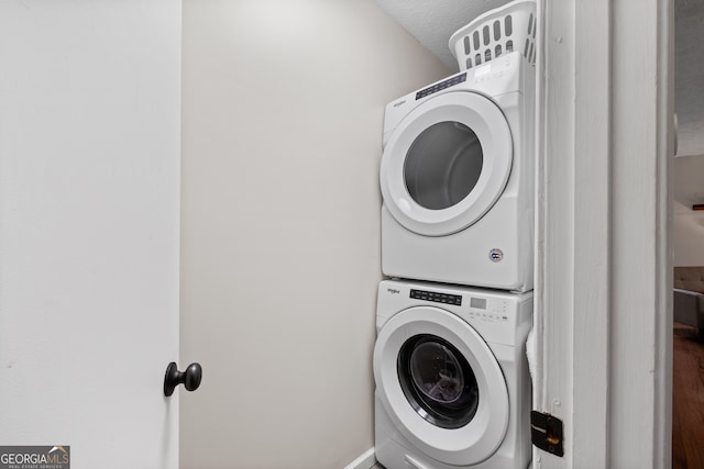 laundry area featuring a textured ceiling and stacked washer / drying machine