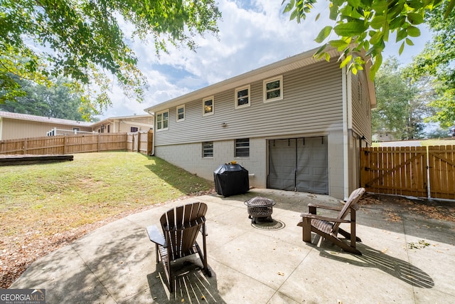 back of house with a garage, an outdoor fire pit, a yard, and a patio area