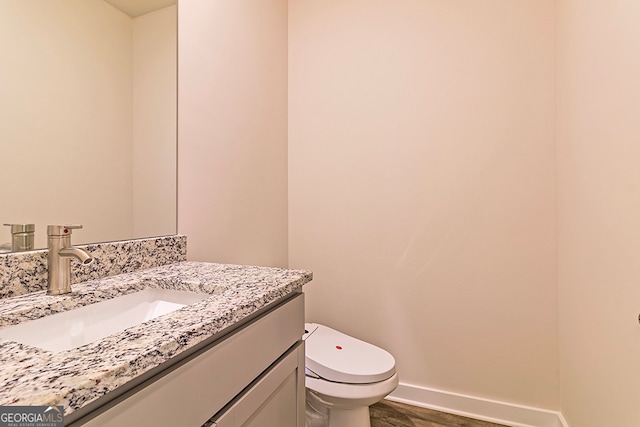 bathroom featuring toilet, hardwood / wood-style flooring, and vanity