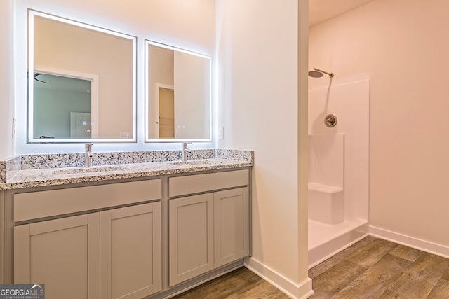 bathroom featuring vanity, walk in shower, and wood-type flooring