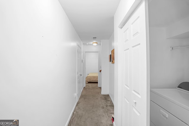 corridor featuring washer / dryer and light colored carpet