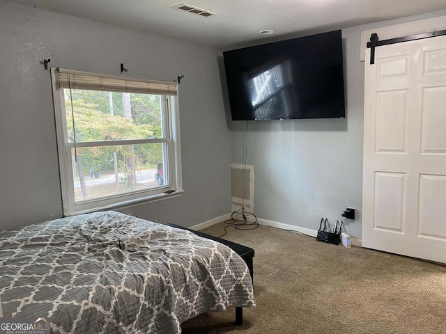 bedroom with a barn door and carpet floors