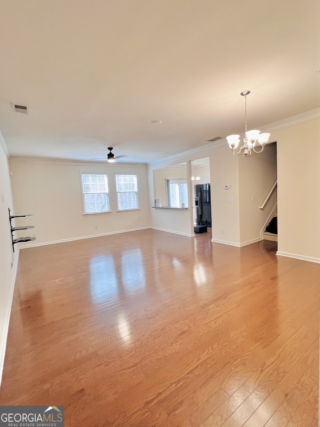 unfurnished living room featuring ceiling fan with notable chandelier, ornamental molding, and hardwood / wood-style flooring