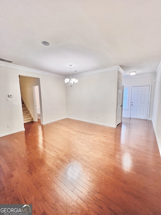 unfurnished room with wood-type flooring, ornamental molding, and an inviting chandelier